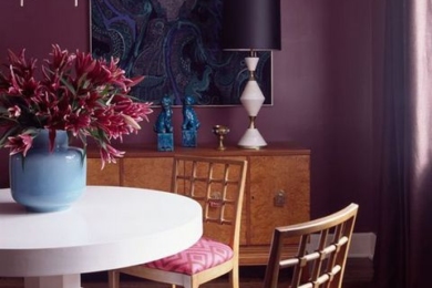 кімната із фіолетовою стіною, білим столом та рожевими стільцями